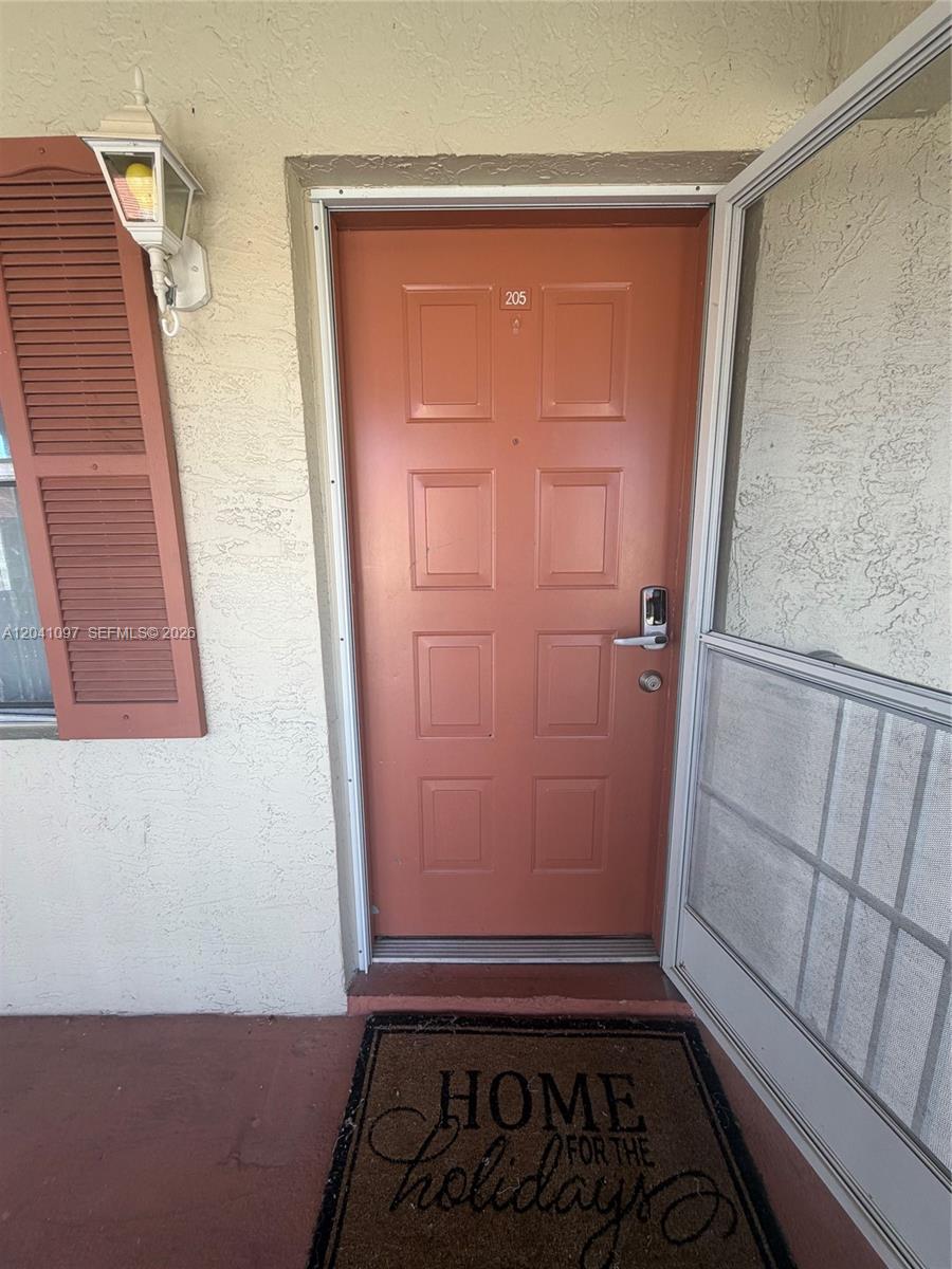 A terracotta-colored front door with the number 205 is shown from an exterior entryway — 3031 Holiday Springs Blvd # 7, Margate FL 33063, MARGATE, FL