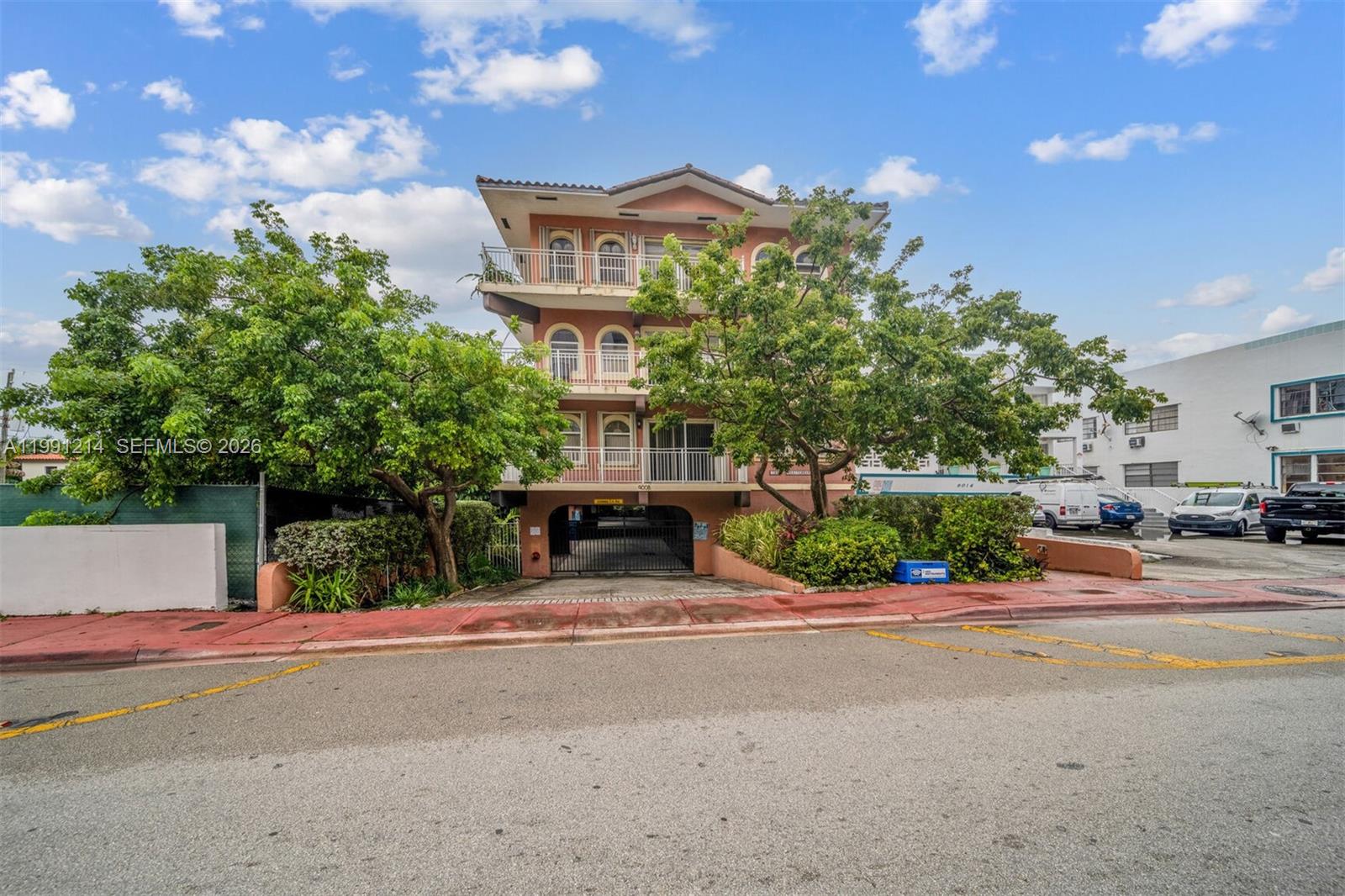 A three-story peach-colored apartment building features arched balconies and a ground-level gated parking garage — 9008 Collins Ave # 402, Surfside FL 33154, SURFSIDE, FL