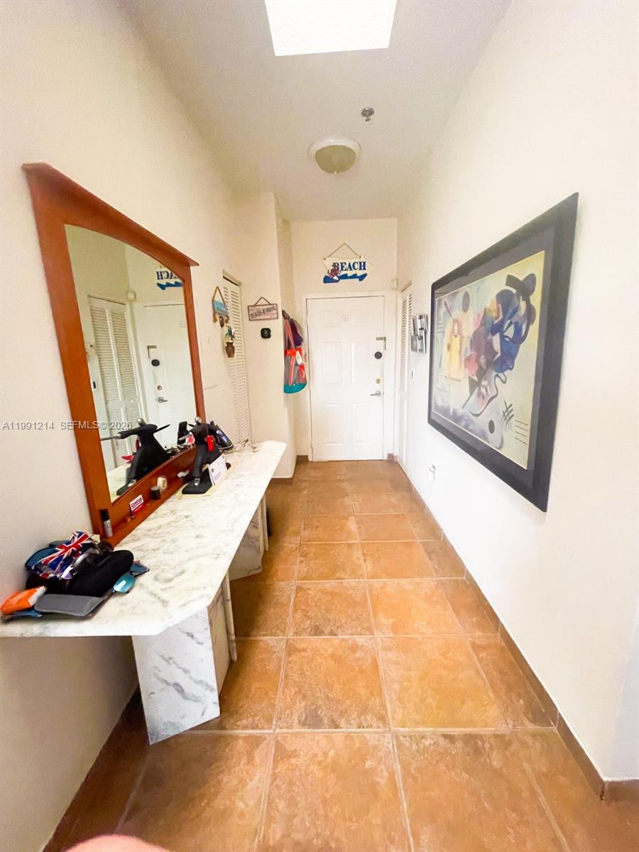 A hallway features a marble-topped console table, a large mirror, and tile flooring — 9008 Collins Ave # 402, Surfside FL 33154, SURFSIDE, FL