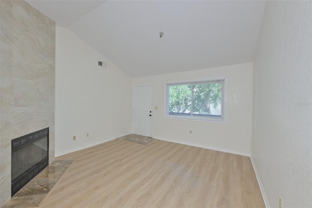 A living room features light wood-look flooring, a tiled fireplace, and a white entry door — 10265 GANDY BOULEVARD N UNIT 1006, ST PETERSBURG, FL