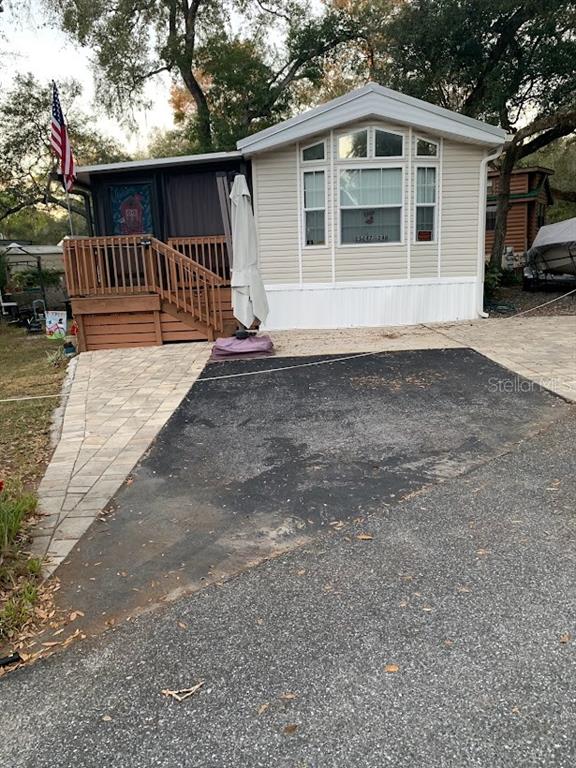 A manufactured home with a wooden deck, a paved walkway, and an asphalt driveway — 25247 NE 141ST LANE UNIT 248, FORT MC COY, FL