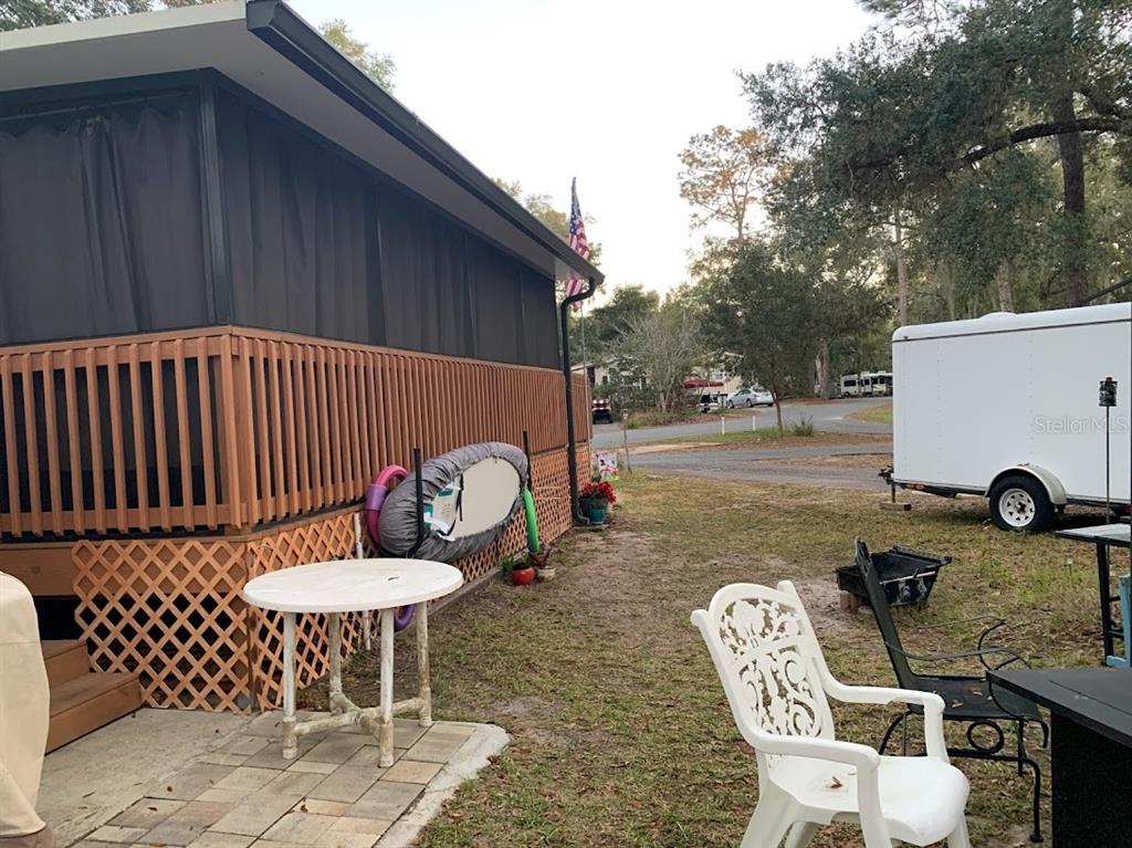 A white table and chair sit on a patio beside a house with wooden lattice — 25247 NE 141ST LANE UNIT 248, FORT MC COY, FL