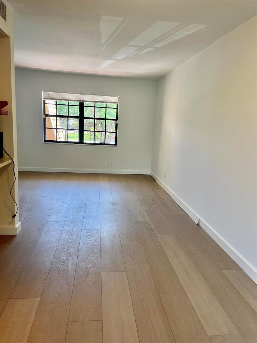 An empty room features light-colored wood flooring, white walls, and a large grid-patterned window — 4243 Oak Terrace Drive # 4243, FL 33463, FL