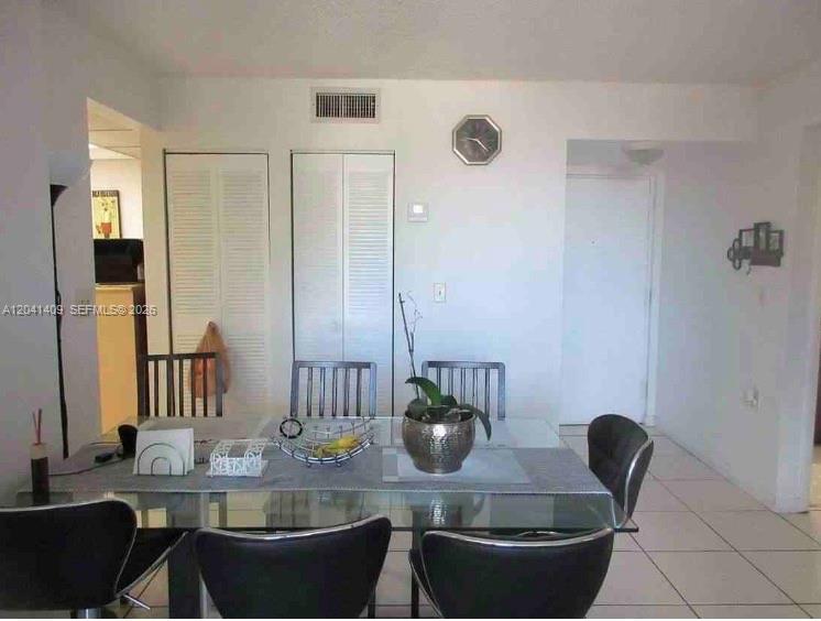 A dining room with a glass-top table, black chairs, and white louvered closet doors — 3601 SW 117th Ave # 301, Miami FL 33175, MIAMI, FL