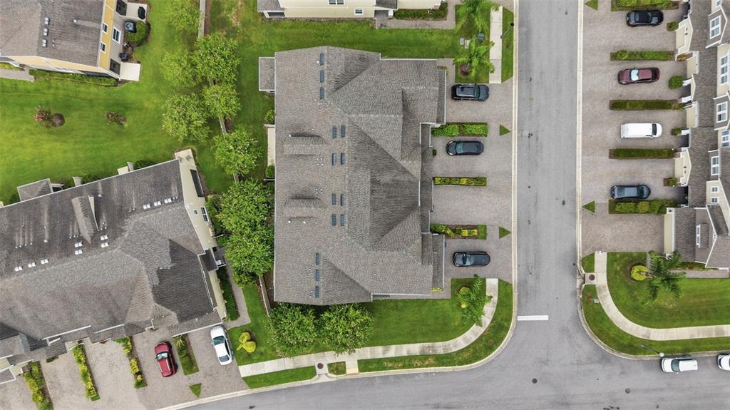 An aerial view shows a multi-unit residential building with parking spaces and surrounding green lawns — 18924 ULMUS STREET, LUTZ, FL