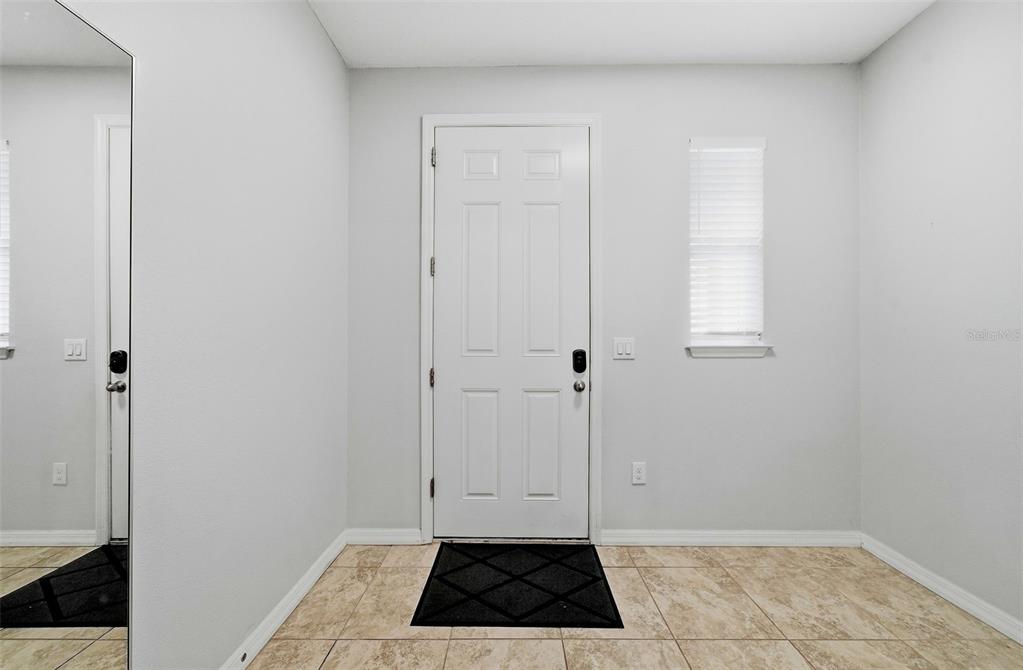 An entryway features a white front door, a window with blinds, and tiled flooring — 18924 ULMUS STREET, LUTZ, FL