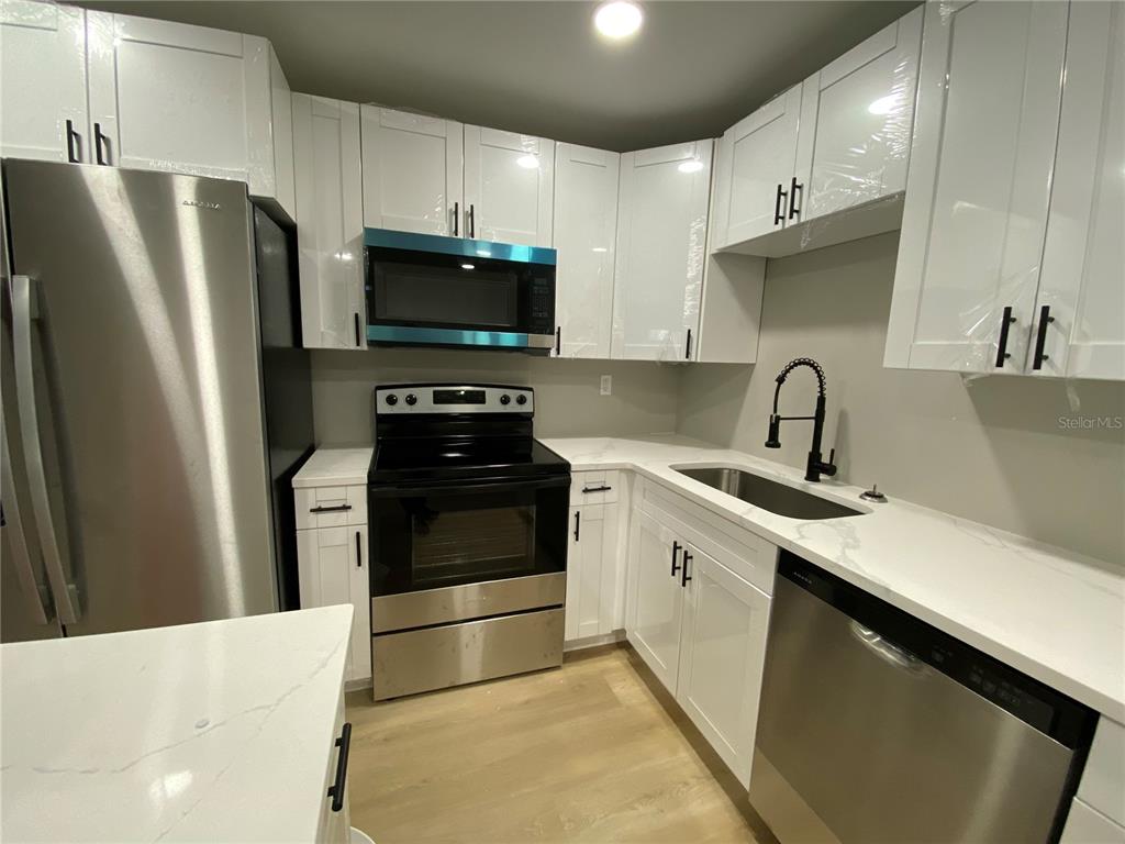 A kitchen features white cabinets, stainless steel appliances, and light-colored countertops — 10005 N 29TH STREET, TAMPA, FL