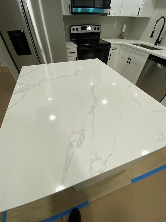 A kitchen features a white marble-patterned island countertop, stainless steel appliances, and white cabinetry — 10005 N 29TH STREET, TAMPA, FL