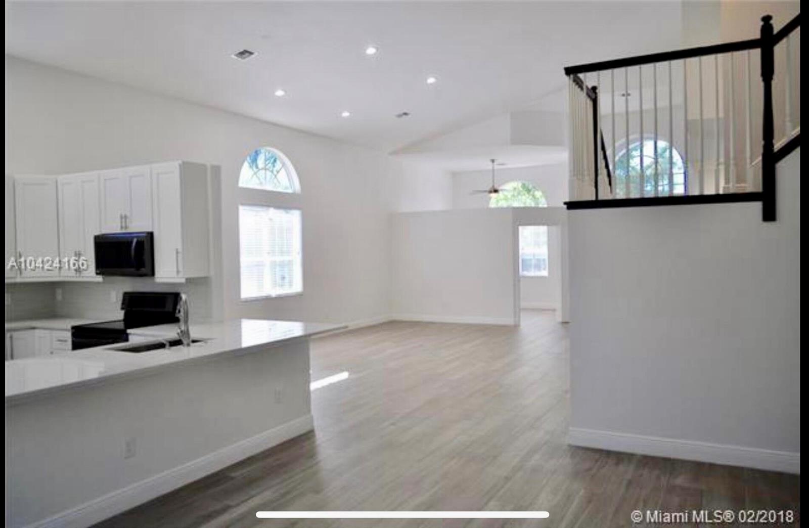 A bright, open-concept kitchen and living area with white cabinets, light flooring, and high ceilings — 5 Lake Eden Drive, Boynton Beach FL 33435, BOYNTON BEACH, FL