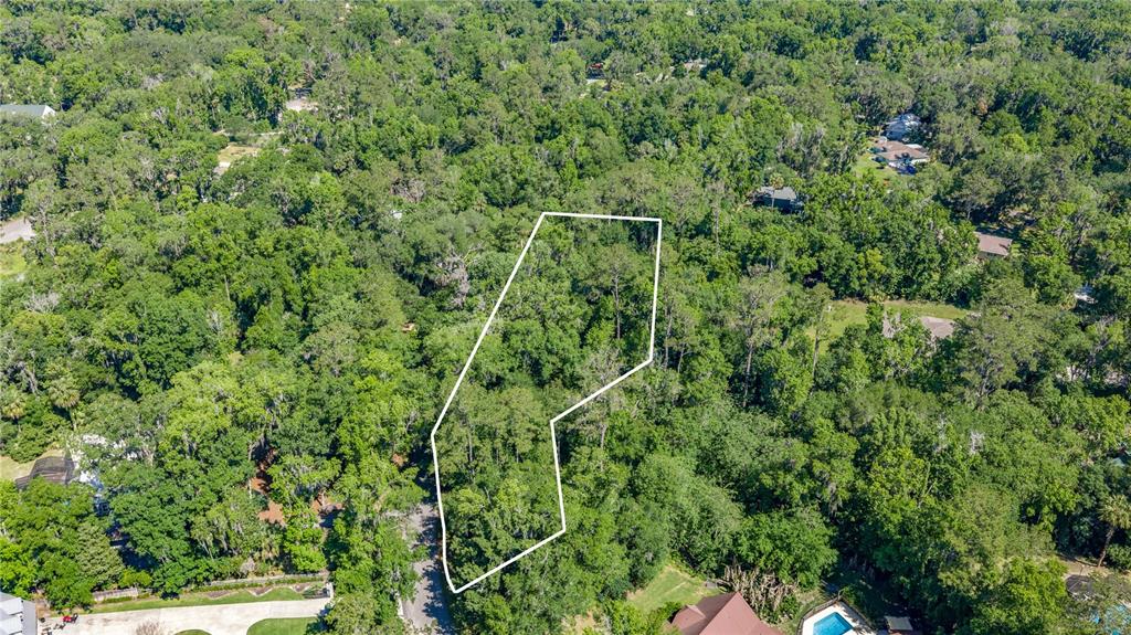 An aerial view shows a wooded residential lot outlined in white against surrounding trees — SW 45TH STREET, OCALA, FL