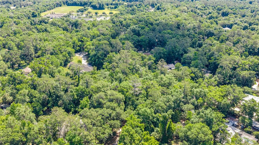 An aerial view shows several houses nestled within a dense, wooded residential area — SW 45TH STREET, OCALA, FL