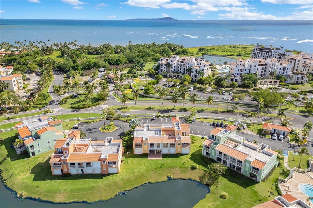 An aerial view shows multi-story residential buildings, a small pond, and coastal scenery — 190 CANDELERO DRIVE UNIT 9247, HUMACAO, PR