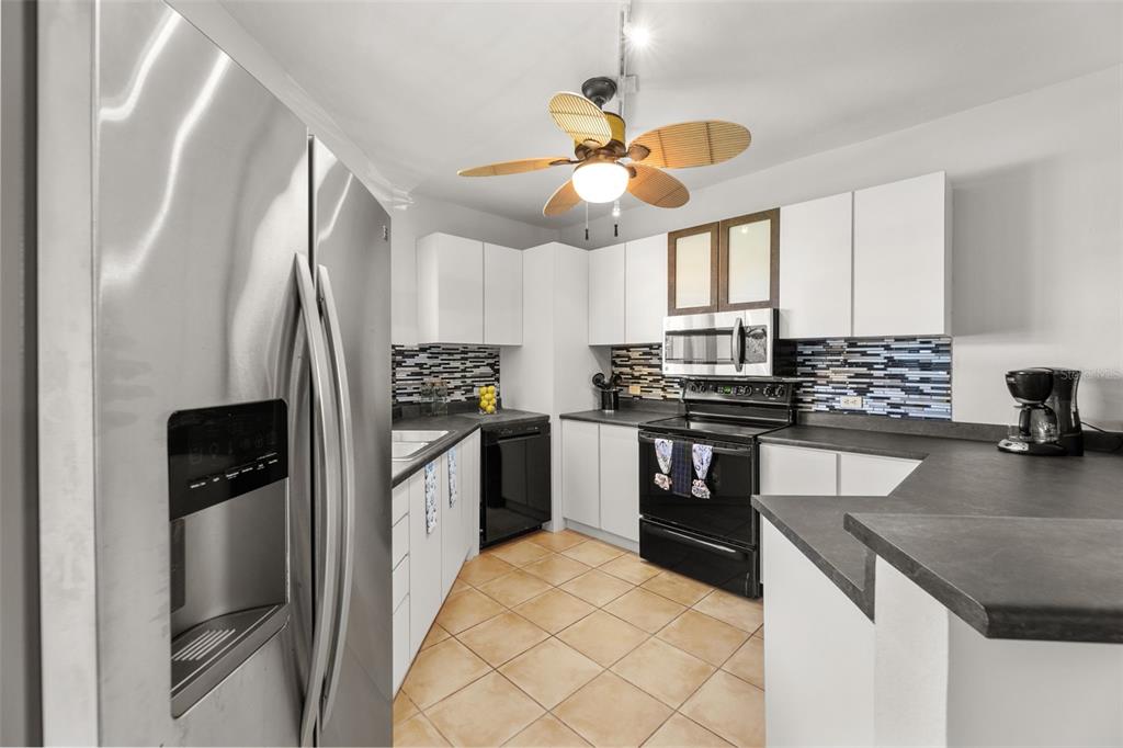 A kitchen features white cabinets, black appliances, a tiled floor, and a ceiling fan — 190 CANDELERO DRIVE UNIT 9247, HUMACAO, PR
