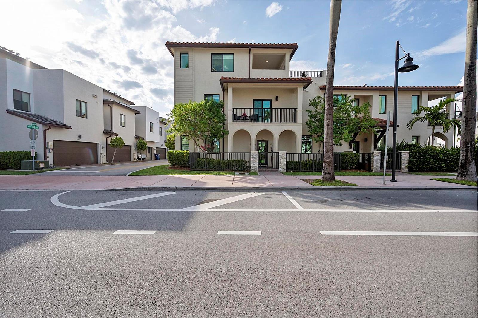 A three-story townhouse with a balcony, arched entryway, and tiled roof sits beside a street — 8321 Central Park Boulevard, Doral FL 33166, DORAL, FL