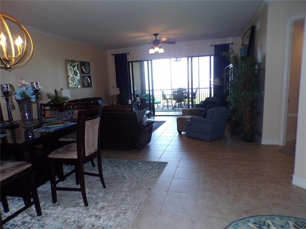 An open-concept living and dining area features tile flooring, a ceiling fan, and balcony access — 89 VIVANTE BOULEVARD UNIT 205, PUNTA GORDA, FL