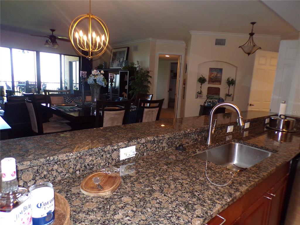 A kitchen with granite countertops and a stainless steel sink overlooks a dining area — 89 VIVANTE BOULEVARD UNIT 205, PUNTA GORDA, FL