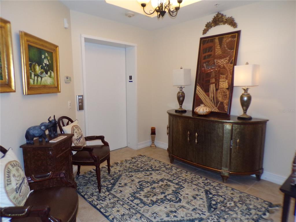 An interior foyer features an elevator, a console table with lamps, and two armchairs — 89 VIVANTE BOULEVARD UNIT 205, PUNTA GORDA, FL