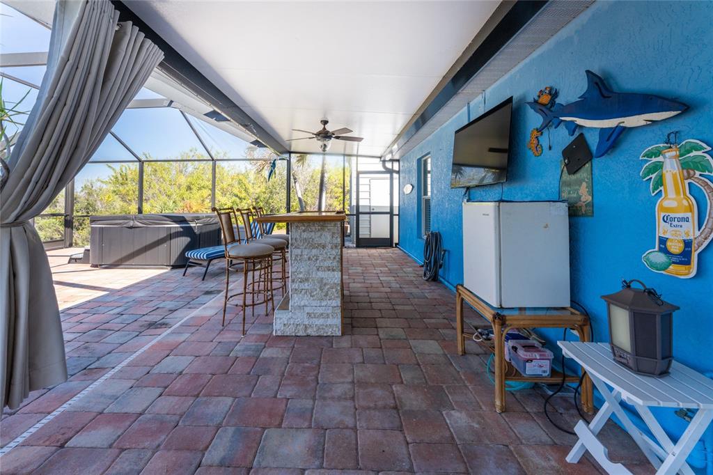 A covered patio features a stone bar, a hot tub, and a blue wall with decor — 9300 MIAMI CIRCLE, PORT CHARLOTTE, FL