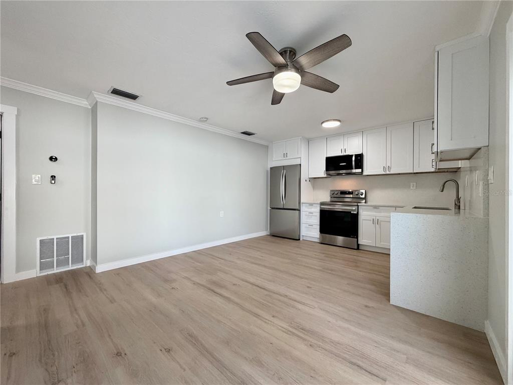 A kitchen with white cabinets, stainless steel appliances, and light wood-look flooring — 13299 3RD STREET E UNIT S, MADEIRA BEACH, FL