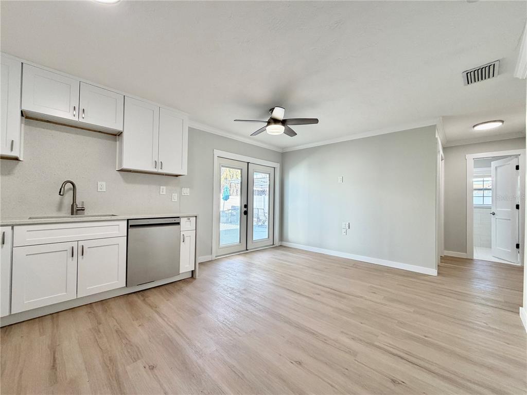 A kitchen and dining area with white cabinets, stainless steel appliances, and light wood flooring — 13299 3RD STREET E UNIT S, MADEIRA BEACH, FL