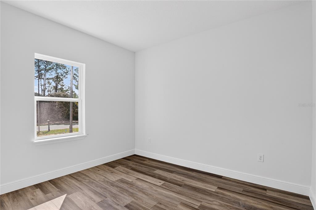 An empty room features light gray walls, white trim, and dark wood-look plank flooring — 1933 W OLIVER DRIVE, CITRUS SPRINGS, FL