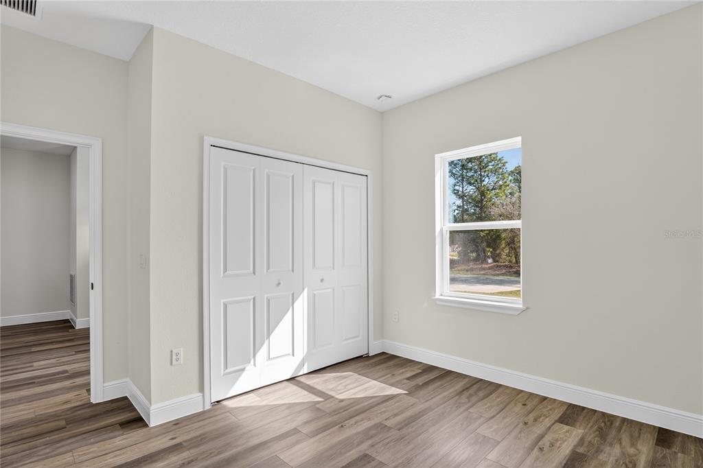 An empty bedroom features light-colored walls, wood-look flooring, a white closet, and a single window — 1933 W OLIVER DRIVE, CITRUS SPRINGS, FL