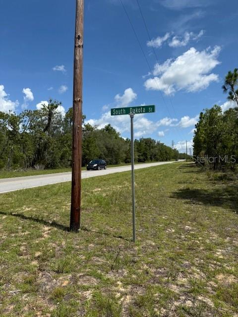 A street sign for South Dakota St stands beside a paved road near trees — 111 S DAKOTA STREET, HAWTHORNE, FL