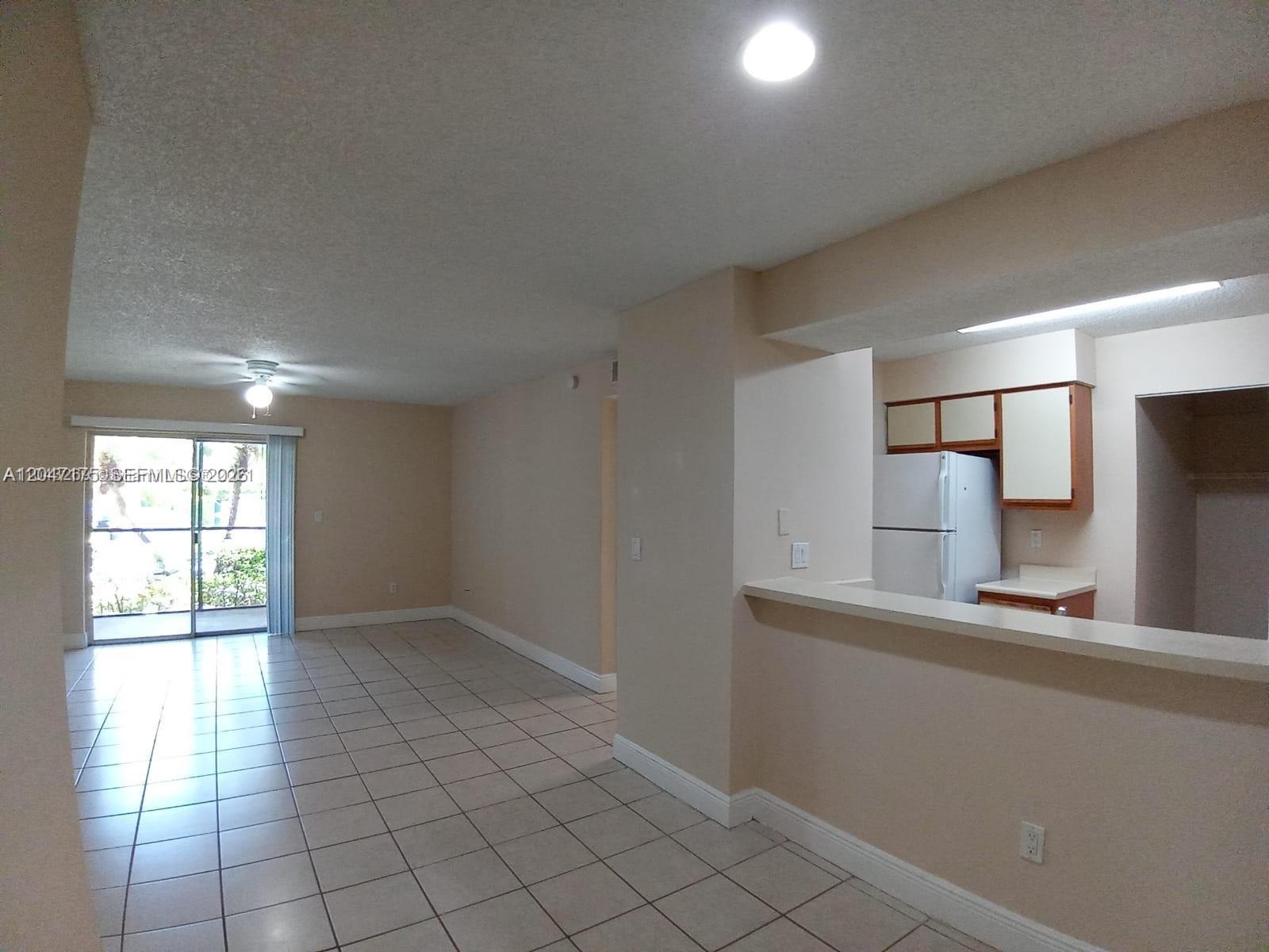 An open-concept living area with tile floors leads to a kitchen with a breakfast bar — POMPANO BEACH, FL