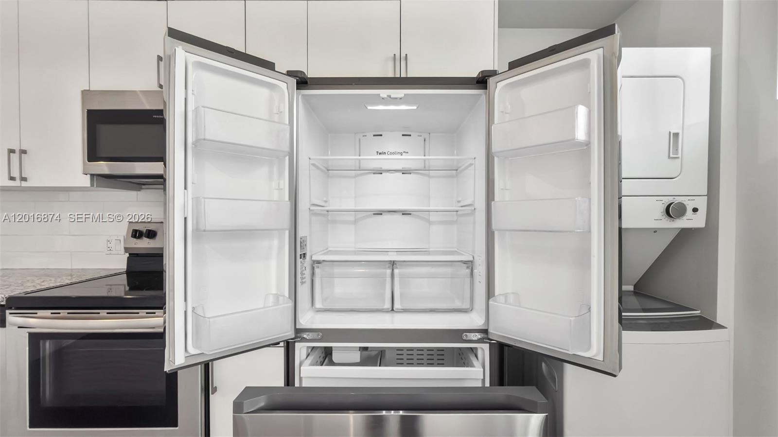A stainless steel refrigerator with open doors sits in a kitchen with white cabinetry — 1536 NW 15th Ave # 206, Miami FL 33125, MIAMI, FL