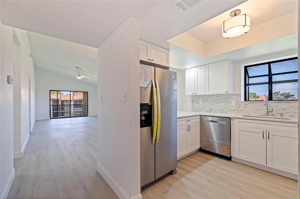 A kitchen with white cabinets and stainless steel appliances opens to a living area — 809 HAMMOCK PINE BOULEVARD, CLEARWATER, FL