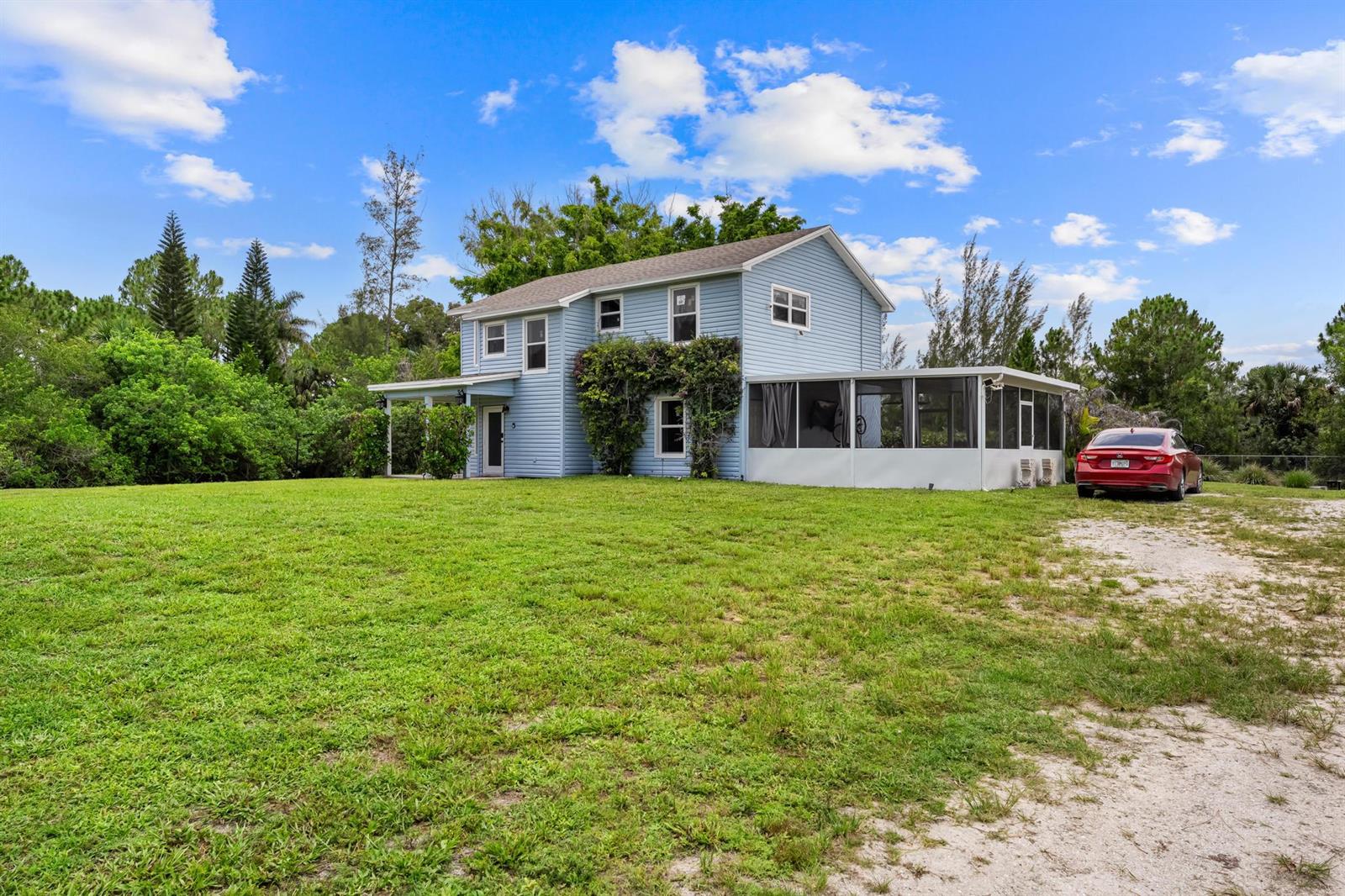 A two-story light blue house with a screened-in porch and a red car parked outside — 16931 93rd Road N, Loxahatchee FL 33470, LOXAHATCHEE, FL