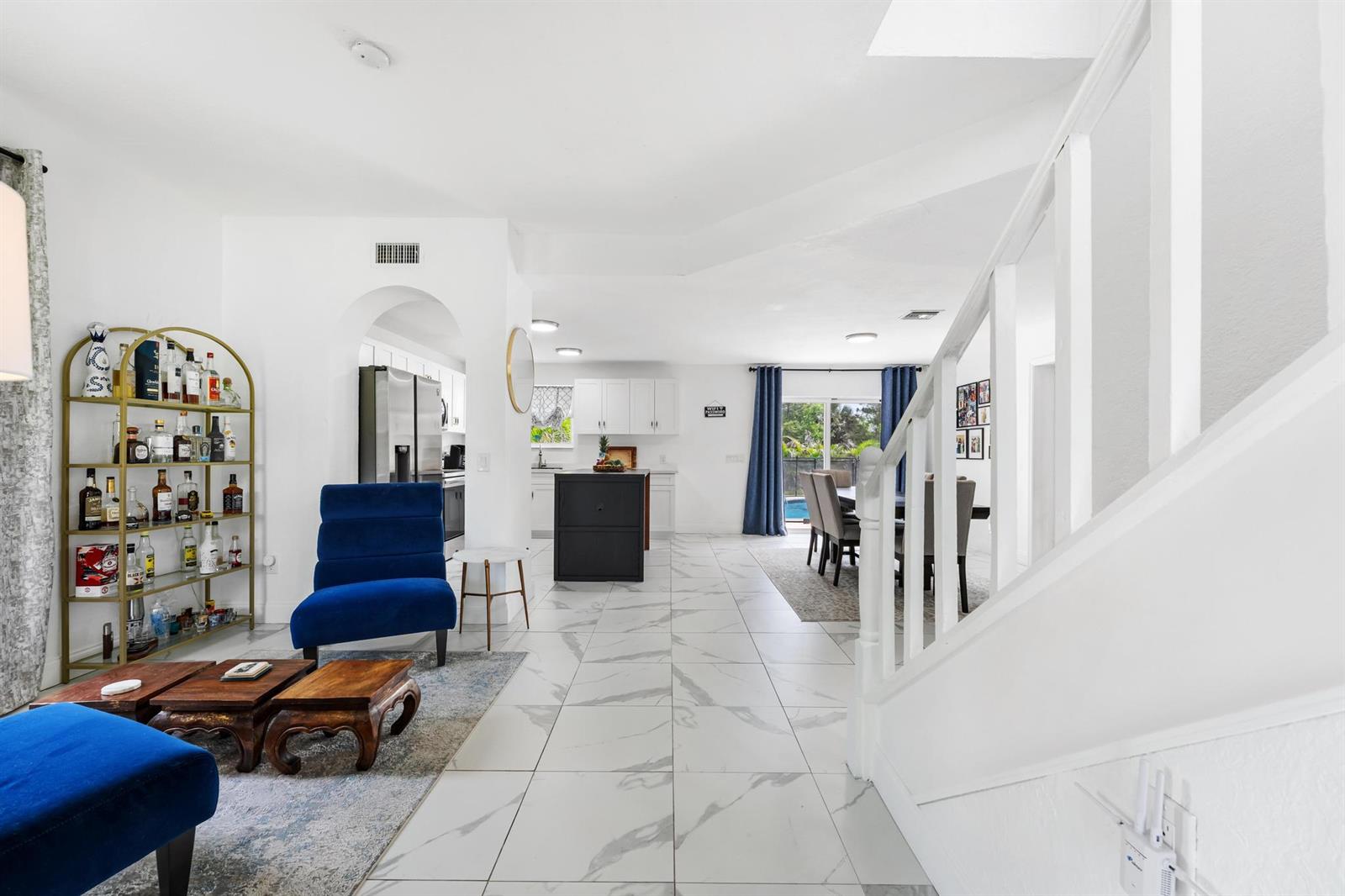 An open-concept living and dining area features white marble-look tile flooring and a blue armchair — 16931 93rd Road N, Loxahatchee FL 33470, LOXAHATCHEE, FL
