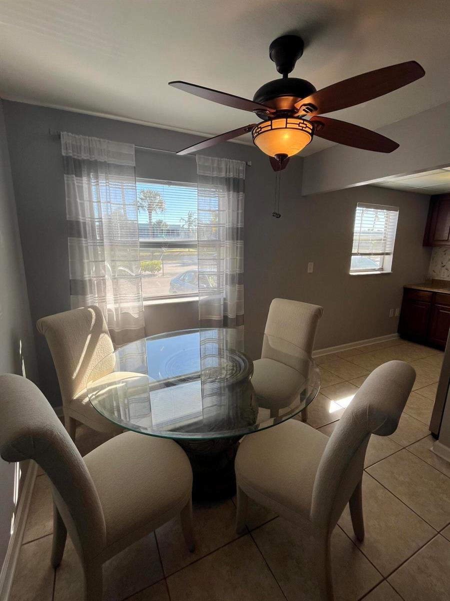 A dining area features a glass-topped table, four upholstered chairs, and a ceiling fan — 289 Brittany G, Delray Beach FL 33446, DELRAY BEACH, FL