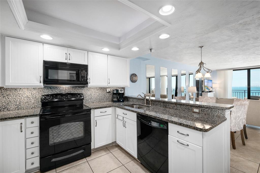 A kitchen with white cabinets, granite countertops, black appliances, and a view of the ocean — 4139 S ATLANTIC AVENUE UNIT B508, NEW SMYRNA BEACH, FL