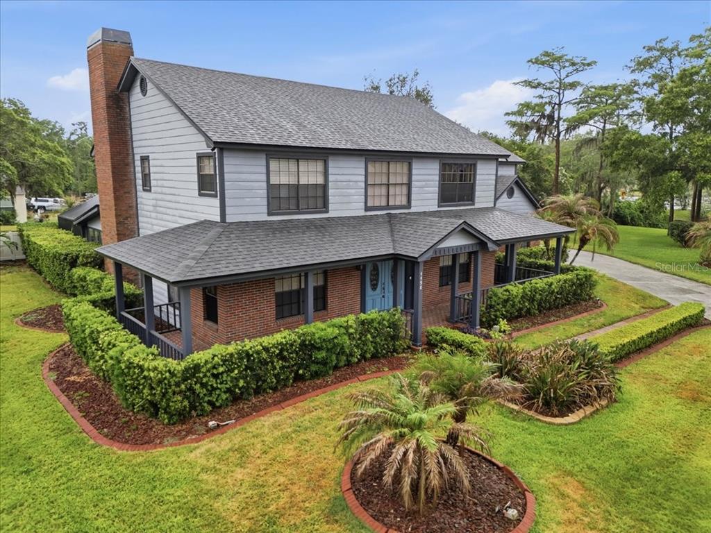 A two-story house with a brick lower level, gray siding, and a wraparound front porch — 4498 REAL COURT, ORLANDO, FL