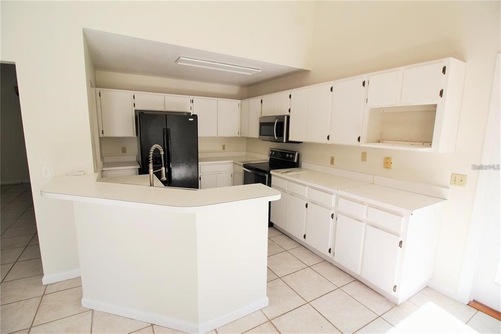 A kitchen with white cabinets, black appliances, and a peninsula counter on a tiled floor — 1309 BLACK WILLOW TRAIL, ALTAMONTE SPRINGS, FL