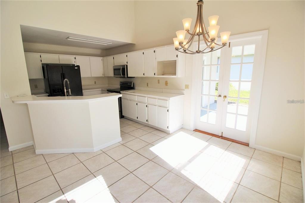 A kitchen with white cabinets, a black refrigerator, tile flooring, and a chandelier — 1309 BLACK WILLOW TRAIL, ALTAMONTE SPRINGS, FL