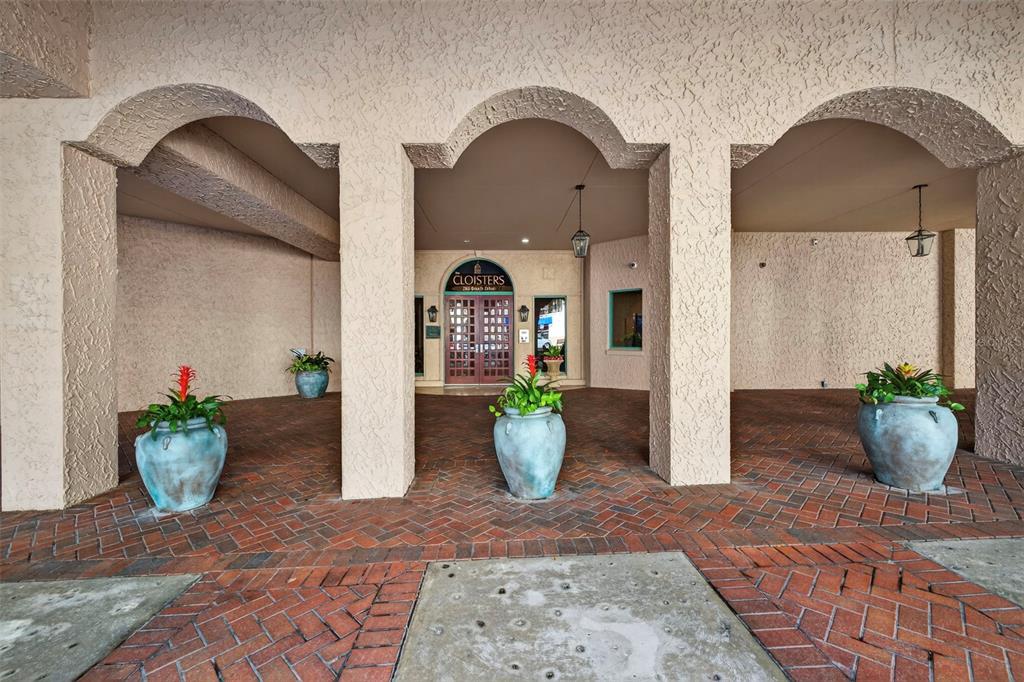 A covered entrance with arched openings, brick flooring, and large potted plants leads to double doors — 288 BEACH DRIVE NE UNIT 4B, ST PETERSBURG, FL