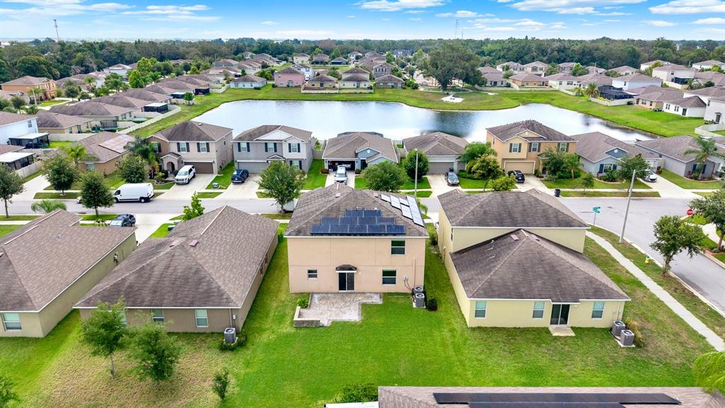 An aerial view shows a suburban neighborhood with houses surrounding a central pond — 10109 CRESTED FRINGE DRIVE, RIVERVIEW, FL