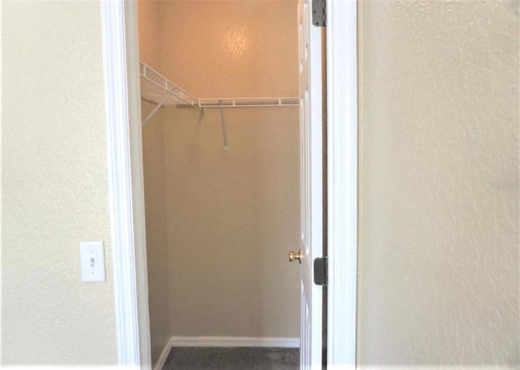 A small walk-in closet features white wire shelving and beige walls — 9435 N MANASHEE DRIVE, CITRUS SPRINGS, FL