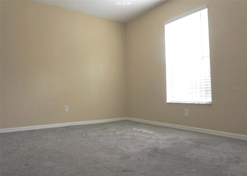 An empty bedroom features beige walls, gray carpeting, and a single window with blinds — 9435 N MANASHEE DRIVE, CITRUS SPRINGS, FL