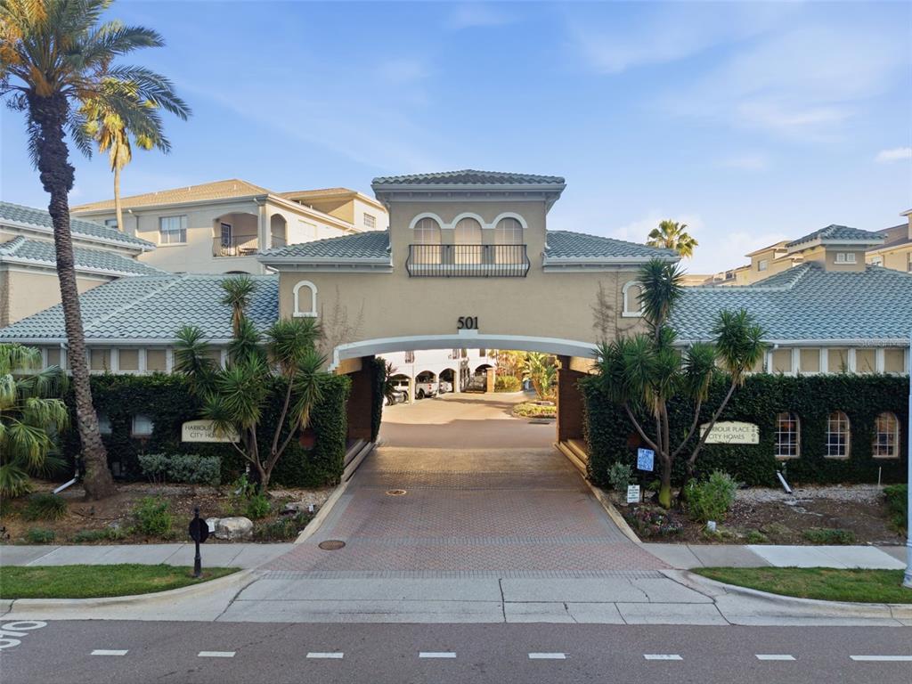 An arched entryway leads into a residential complex with a tan stucco facade and balconies — 501 KNIGHTS RUN AVENUE UNIT 1332, TAMPA, FL