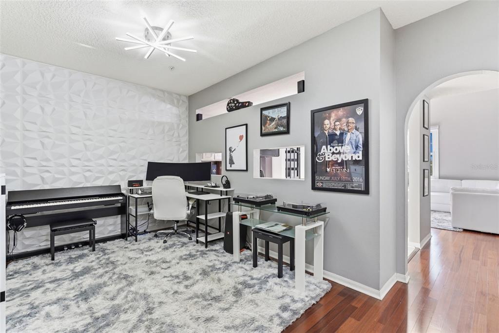 A home office features a digital piano, desk, turntable setup, and a textured accent wall — 501 KNIGHTS RUN AVENUE UNIT 1332, TAMPA, FL