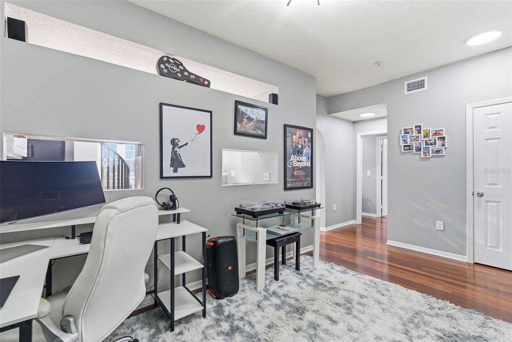 A home office features a desk, turntable stand, wall art, and hardwood flooring — 501 KNIGHTS RUN AVENUE UNIT 1332, TAMPA, FL
