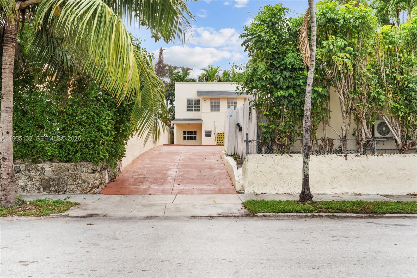 A paved driveway leads to a two-story light-colored house surrounded by lush tropical landscaping — 2385 SW 17th St, Miami FL 33145, MIAMI, FL