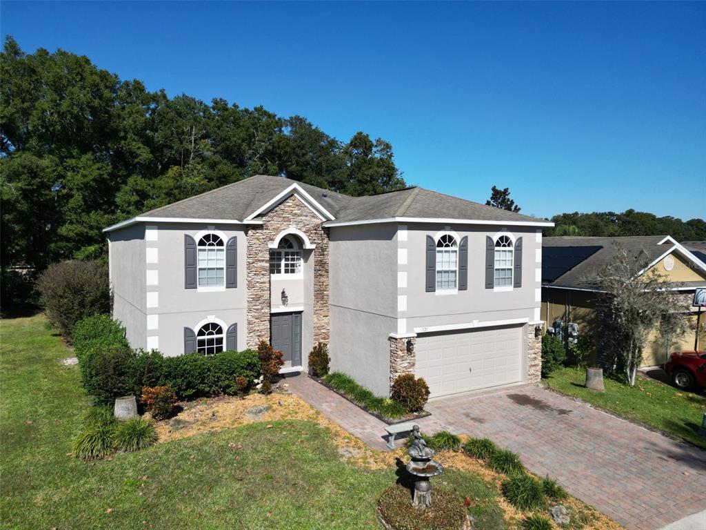 A two-story house with a stone facade, arched windows, and a paved driveway — 121 W FIESTA KEY LOOP, DELAND, FL