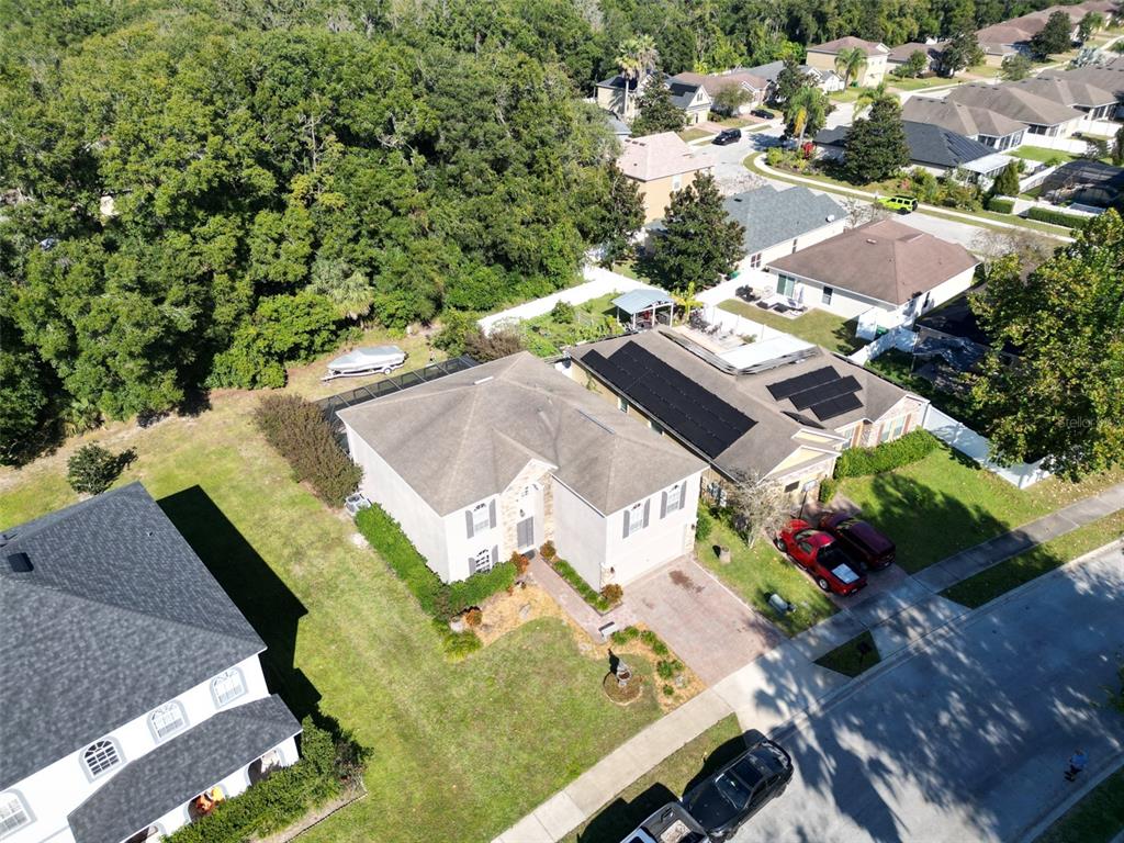 An aerial view shows a suburban house with a paved driveway and solar panels — 121 W FIESTA KEY LOOP, DELAND, FL