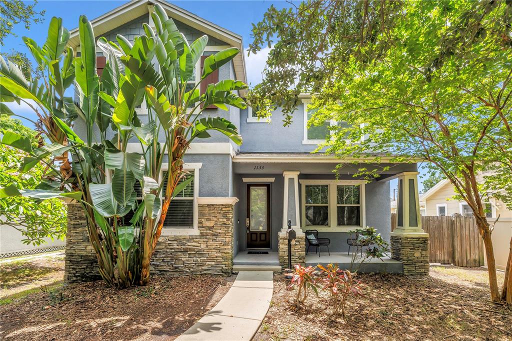 A two-story blue house with stone accents, a front porch, and large tropical plants — 1133 14TH STREET N, ST PETERSBURG, FL