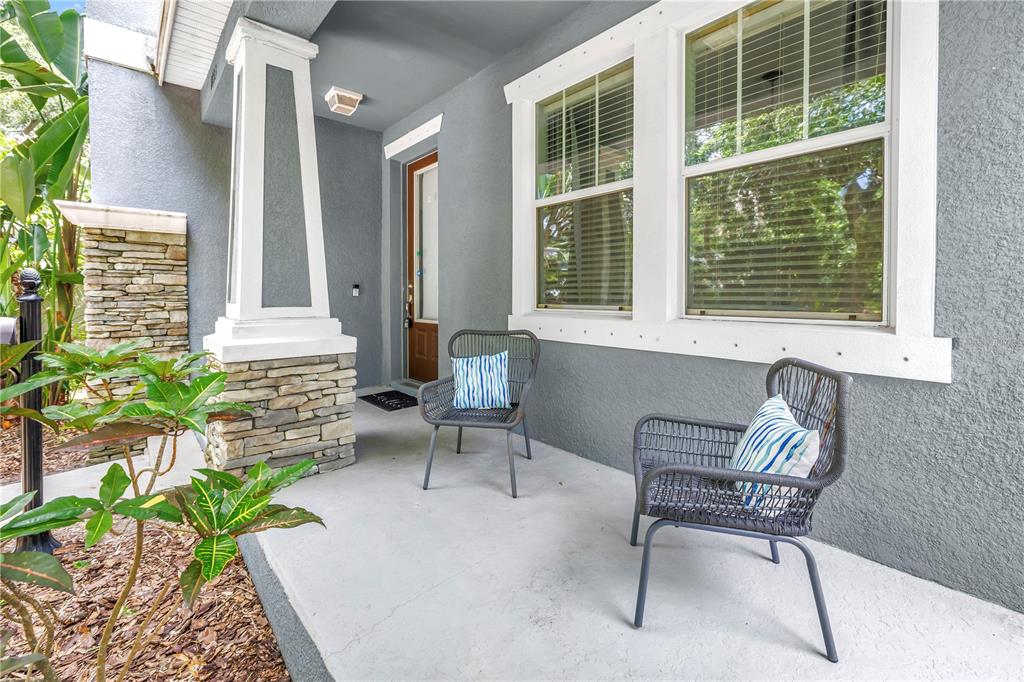 A covered front porch features two gray wicker chairs and a stone-based column — 1133 14TH STREET N, ST PETERSBURG, FL