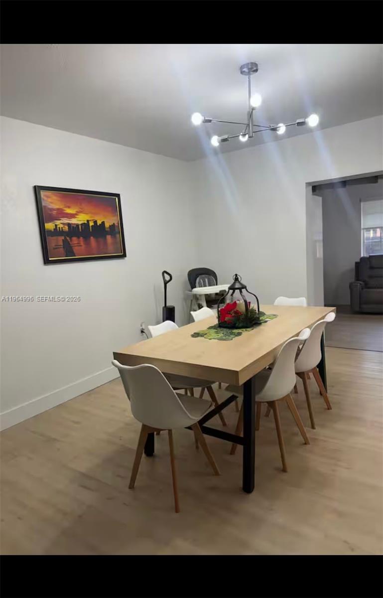 A dining room features a light wood table, white chairs, and a modern chandelier — 508 De Leon Dr, Miami Springs FL 33166, MIAMI SPRINGS, FL
